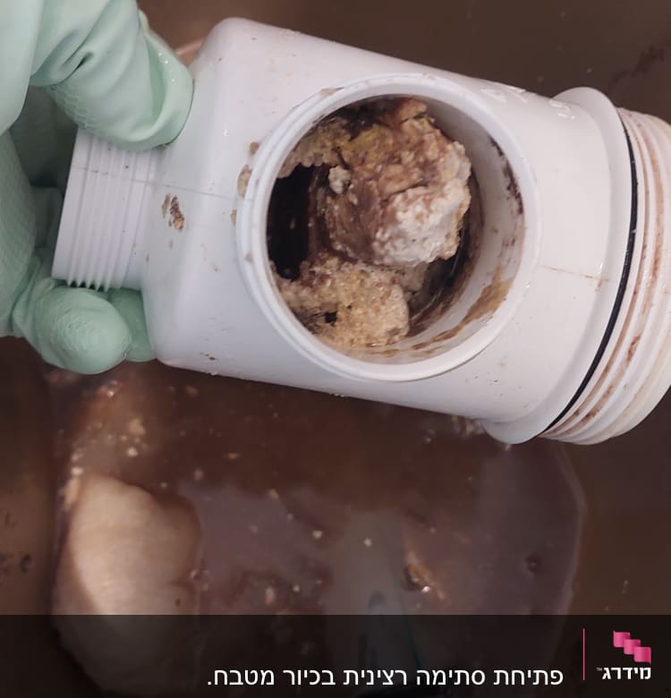 צינור סתום עם לכלוך ביד כפפה ירוקה
